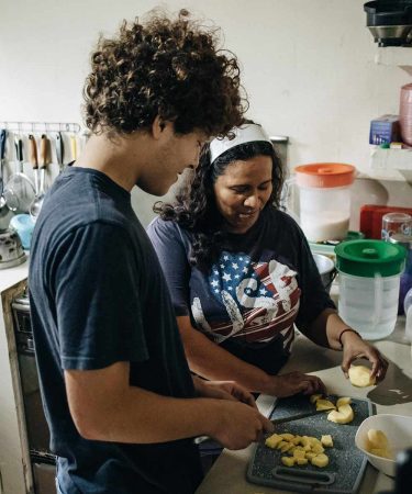 a student and his host mom in the kitchen cutting potatoes
