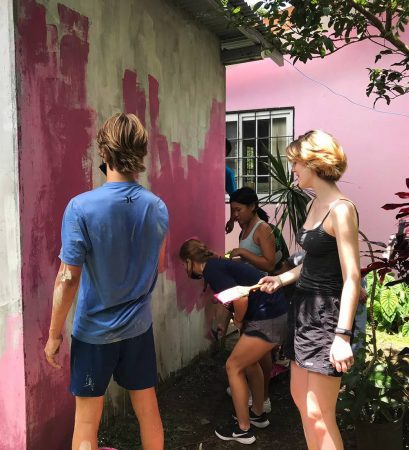 four teens painting a wall pink
