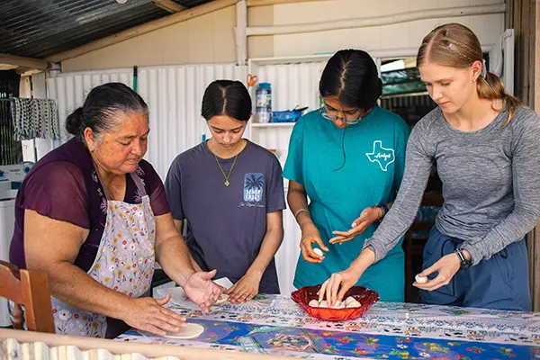 Volunteers making tortillas with their host mom