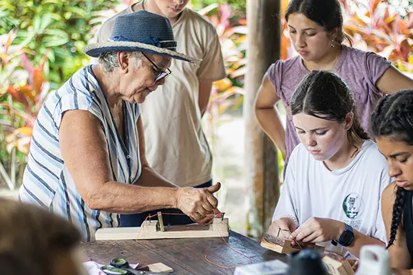 Volunteers making bracelets with local grandma