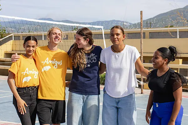Volunteers and local youth laughing in a volleyball court