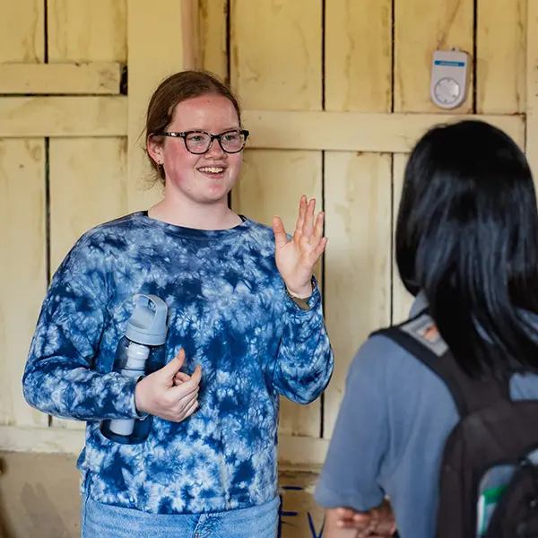 Young volunteer smiling and gesturing while talking with a colleague