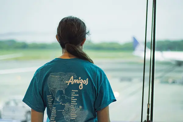 AMIGOS volunteer in a blue shirt looking out an airport window