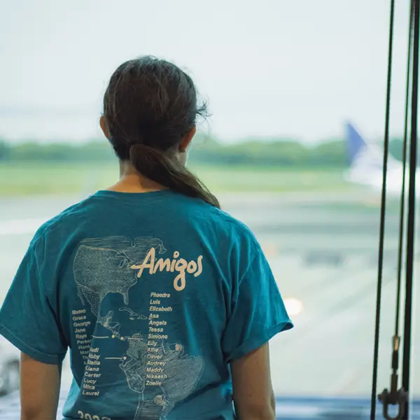 AMIGOS volunteer in a blue shirt looking out an airport window
