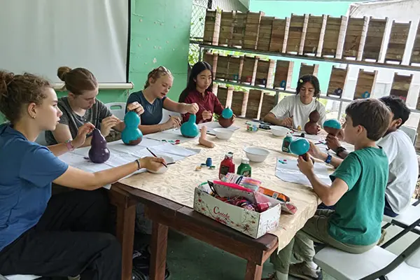 Volunteers painting gourds around a large table during a craft workshop