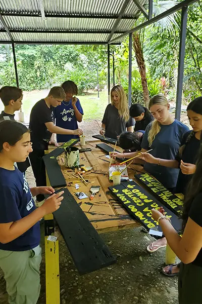 Group of volunteers painting yellow lettering on wooden signs