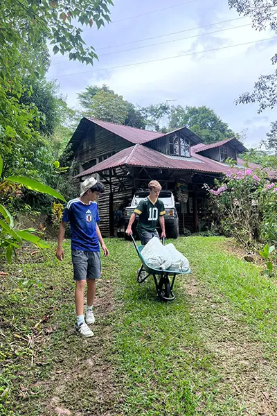 Volunteers transporting supplies in a wheelbarrow across a grassy yard
