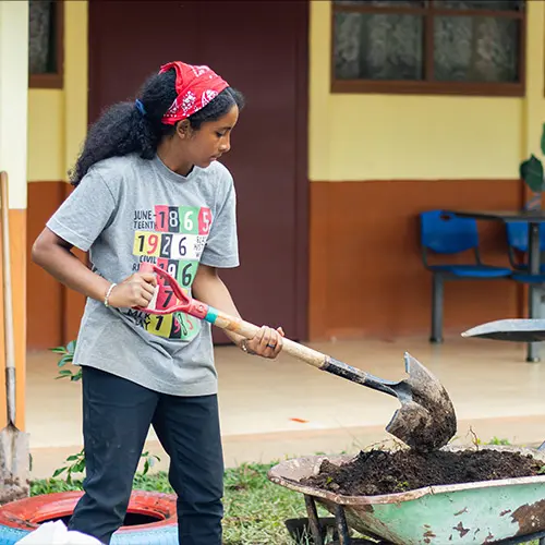 Volunteer doing hands-on service work outdoors with a shovel and wheelbarrow