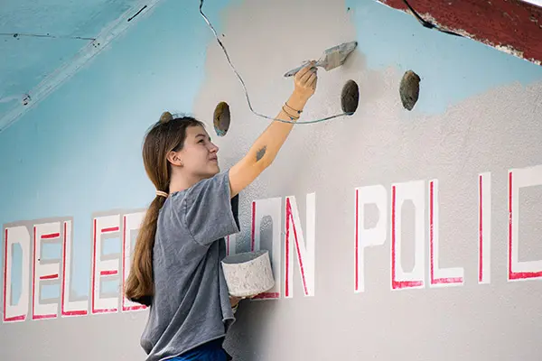 Volunteer painting the exterior wall of a community building
