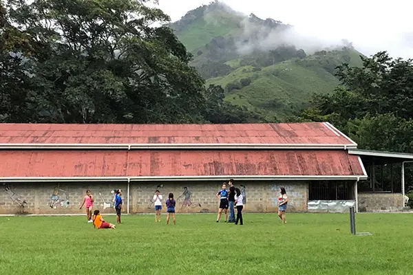 Volunteers and locals playing on a green field in a rural valley