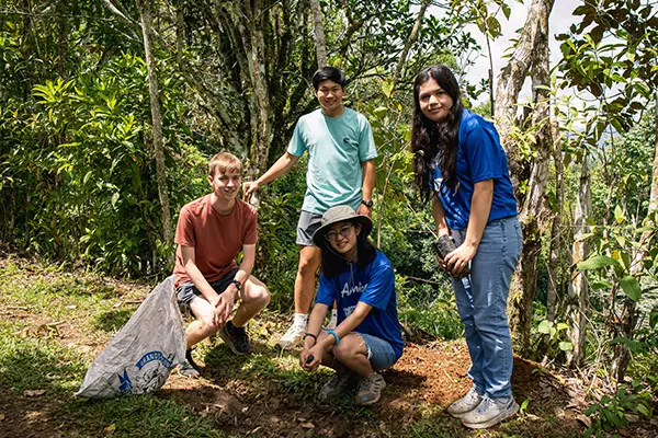 Volunteers planting trees outdoors near a wooded area