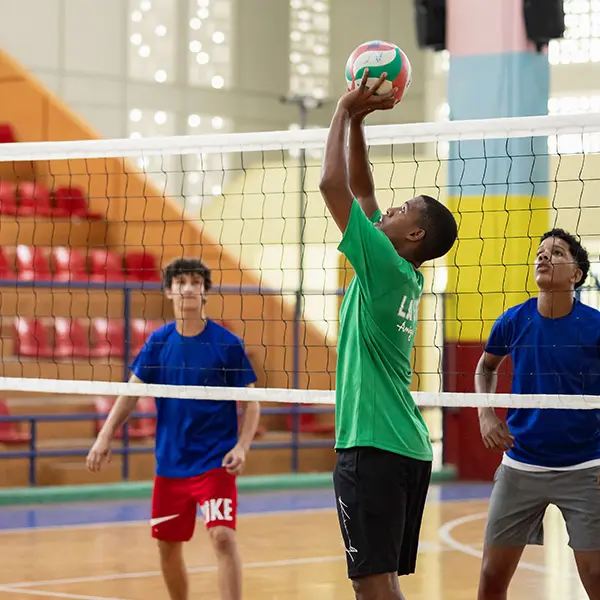 Local youth and AMIGOS volunteer playing volleyball