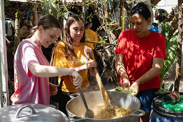AMIGOS volunteers cooking with a host mom