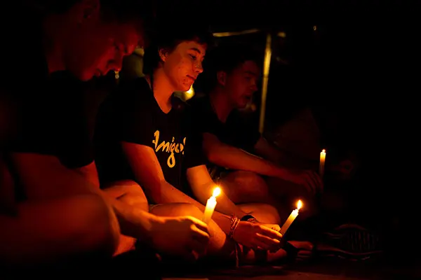 Volunteers holding lit candles during a nighttime reflection activity
