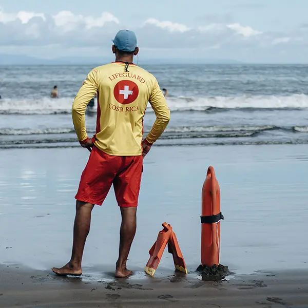 Lifeguard standing on a beach shore with safety rescue equipment