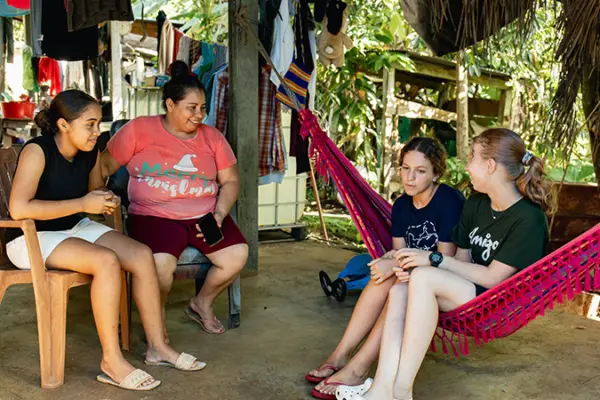 Volunteers and host family members relaxing and chatting under a patio with a hammock