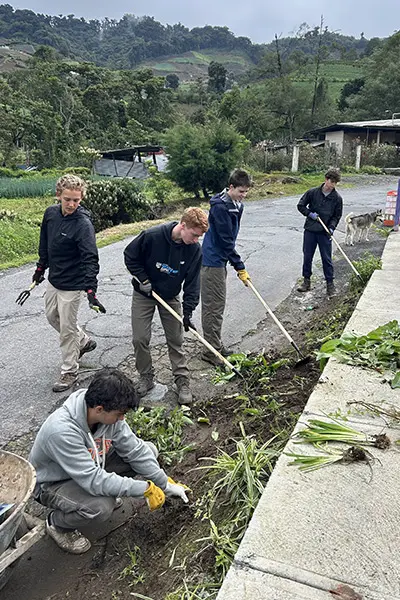 Group of volunteers doing outdoor yard work along a roadside