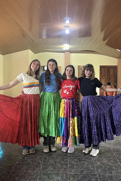 Smiling volunteers posing in colorful traditional skirts
