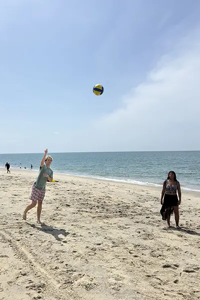 Volunteers playing volleyball at the beach during Debriefing