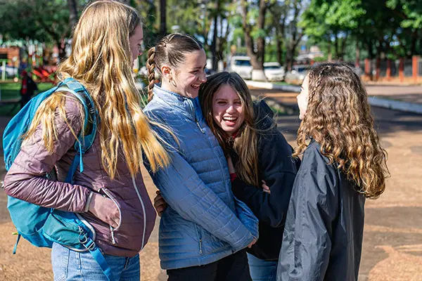 Cuatro jóvenes voluntarias riendo y abrazándose al aire libre