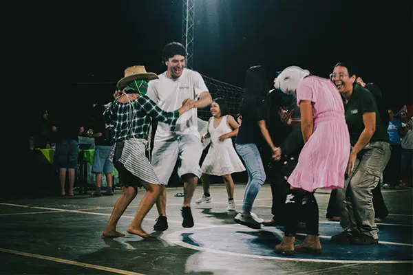 Volunteers and community members dancing and celebrating together during an evening event