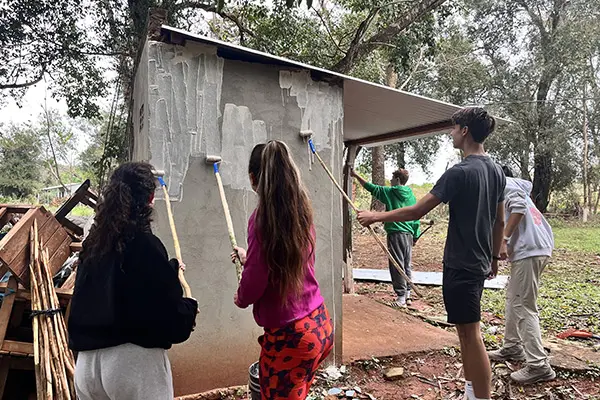 Group of youth volunteers painting a concrete wall with paint rollers