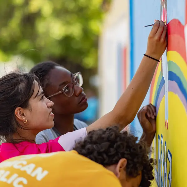 Voluntees paint mural as part of an activity service
