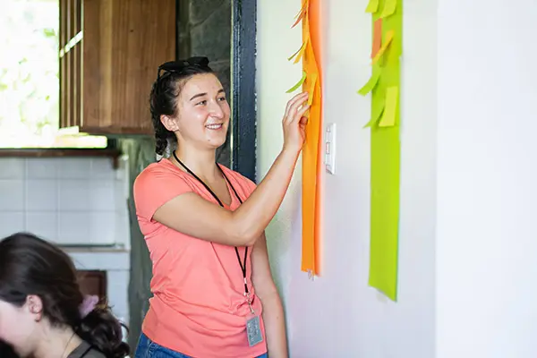 Volunteer placing sticky notes on a wall during an interactive briefing session