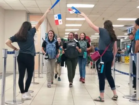 Volunteers wearing backpacks welcomed with Panamanian flags at the airport