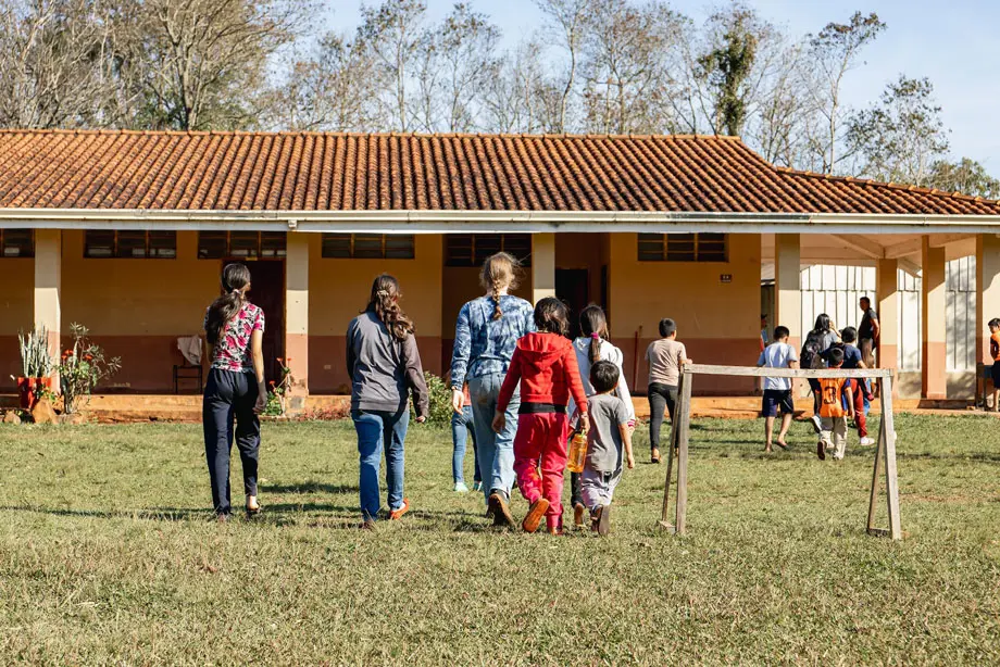 A group of kids playing a soccer game, they are playing on a homemade field and having fun.