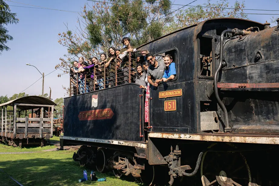 A group of people smile from a decommissioned train, they are at a museum 